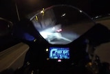 The view from a motorbike with the digital speedo and a ute in front