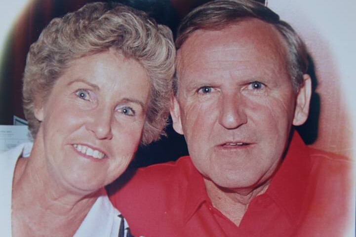 Middle-aged couple look out from heart-shaped photograph