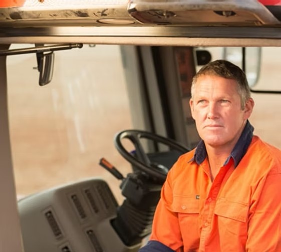 A man in a hi-vis polo shirt sitting in a tractor