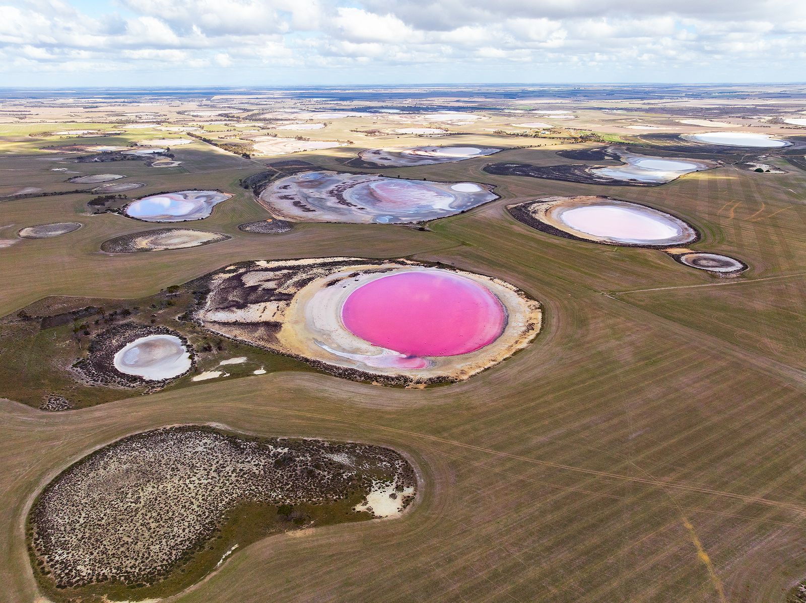 Uma foto aérea de vários lagos em diferentes tons de rosa e branco.