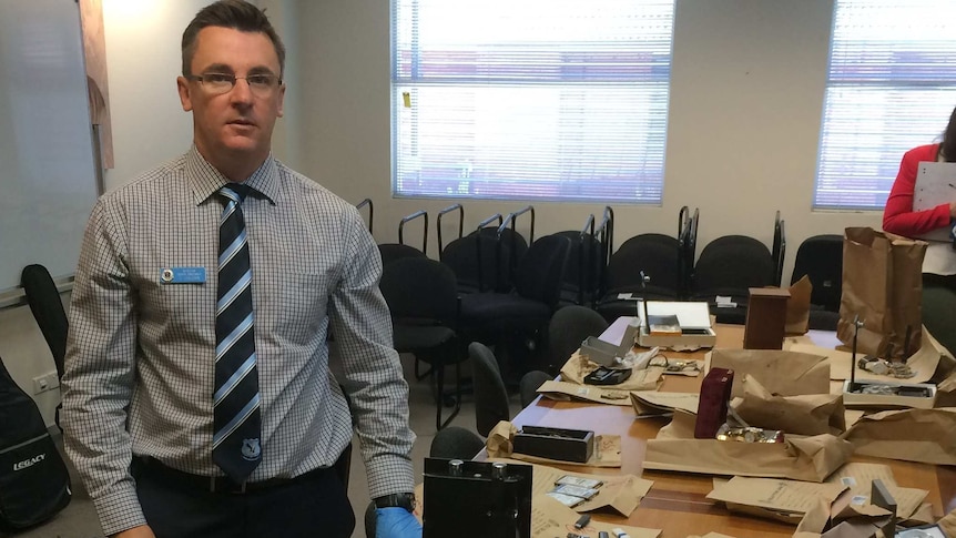 Policeman stands beside bags of evidence