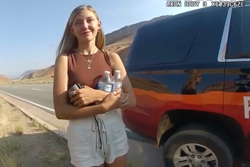 Gabby Petito stands near a police vehicle talking to an office in police bodycam footage.