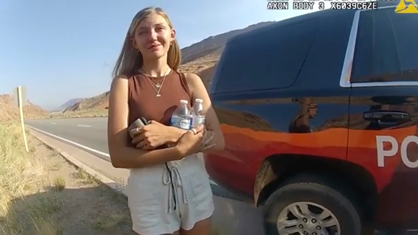Gabby Petito stands near a police vehicle talking to an office in police bodycam footage.