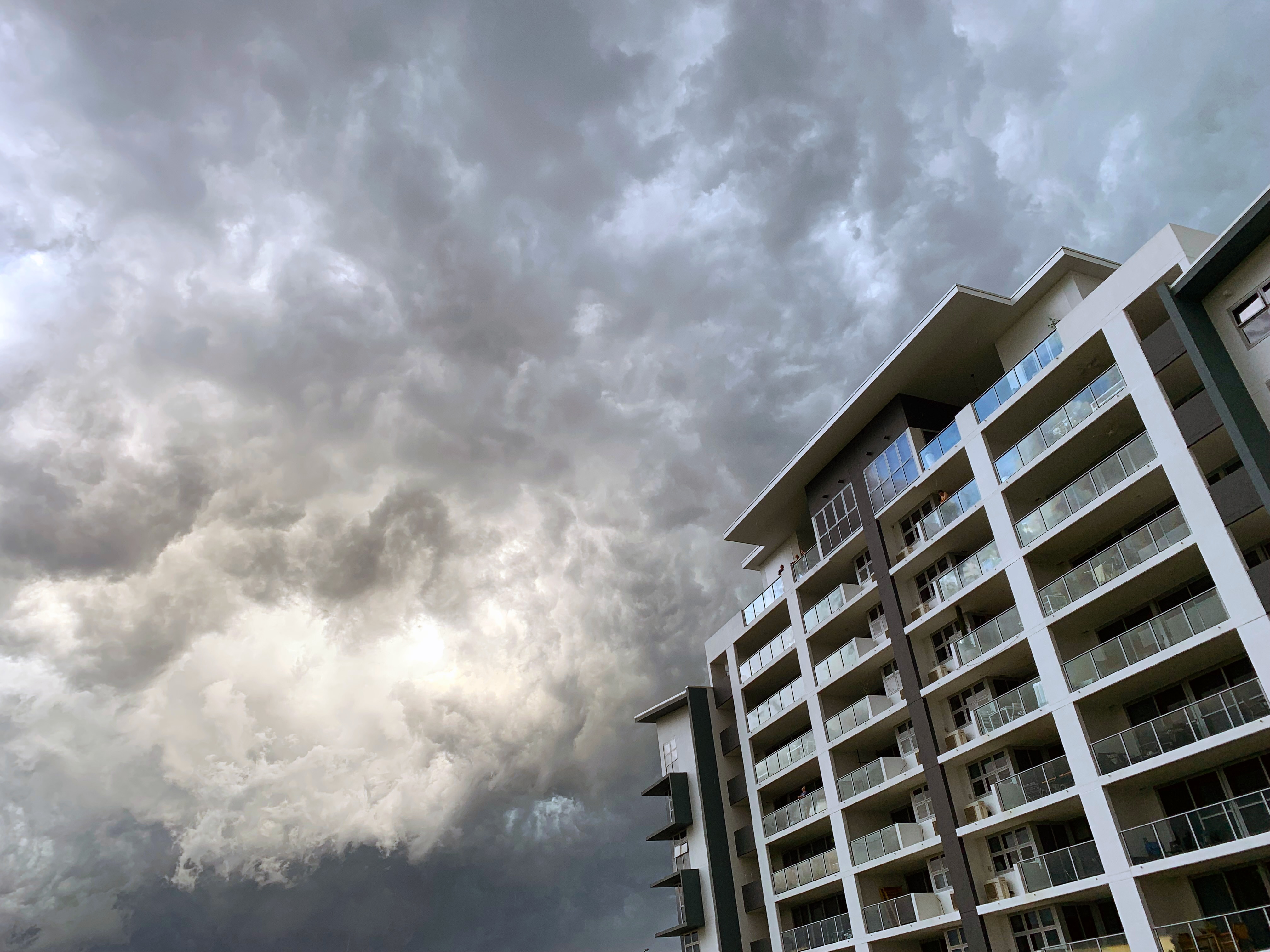 a high rise building with dark storm clouds in the background