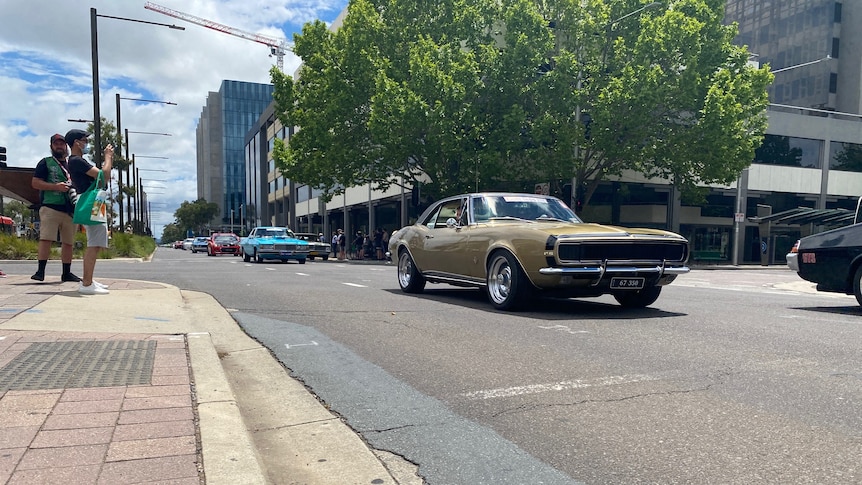 Several hot rods drive down a Canberra street.