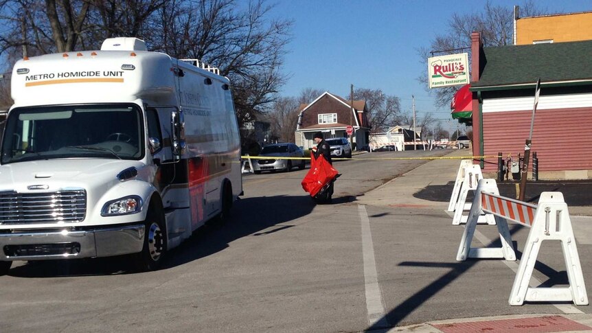 A police investigator walks toward a large white van with Metro Homicide Unit written on the front of it