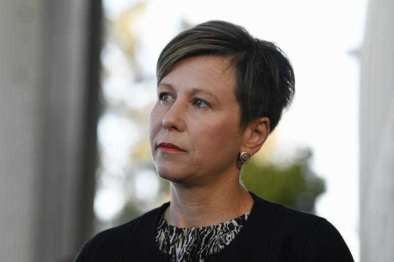 A woman with short brown hiar and silver earrings.