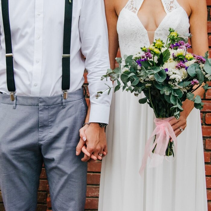 A newly married couple hold hands at their wedding.