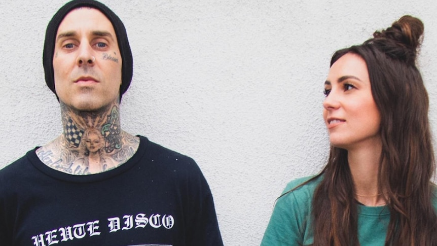 Image of Travis Barker (in black tee and beanie) and Amy Shark (in green tee)