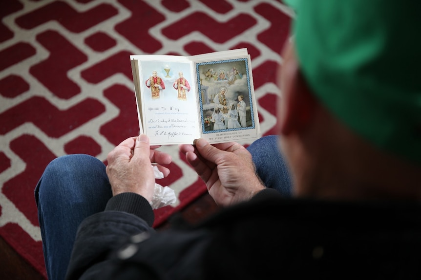 A man holds a booklet as he is pictured from behind