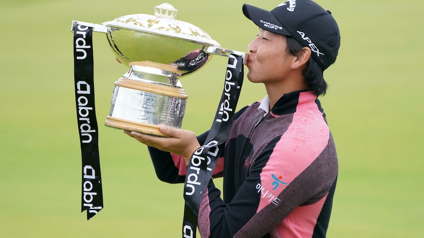 Golfer holds a trophy to his lips and kisses it after winning a tournament.