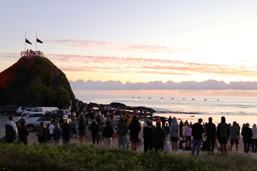 People gather on a beach at dawn.