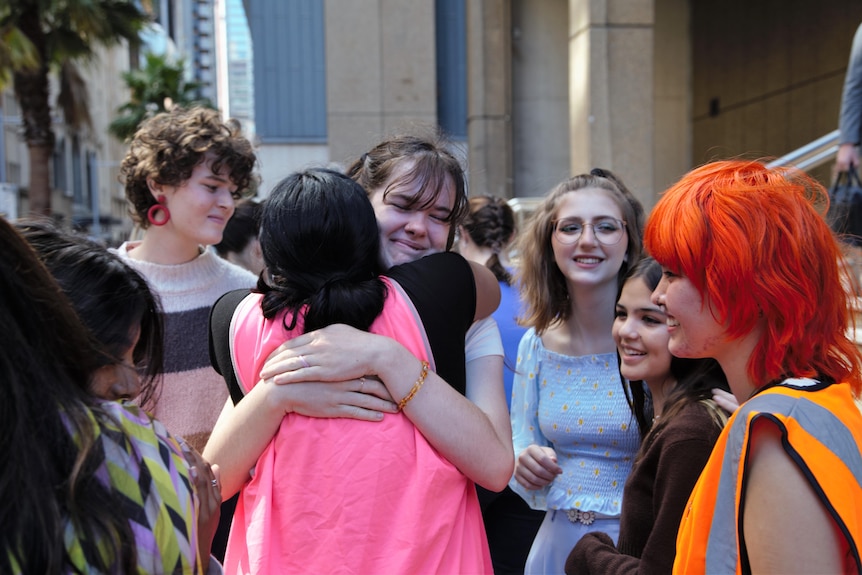 A group of teenagers hugging outside the federal court in Sydney.