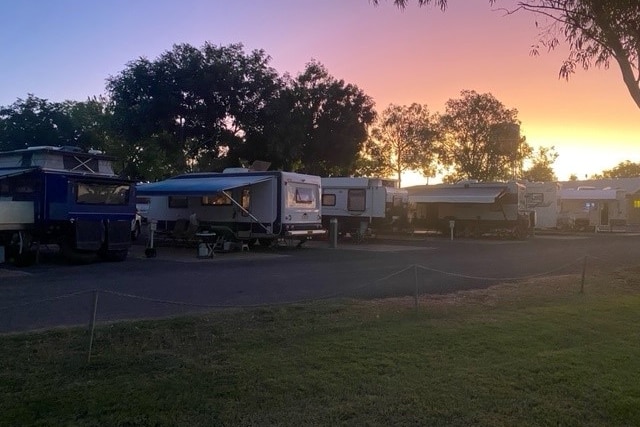 Un parc de caravanes animé avec un coucher de soleil en arrière-plan. 