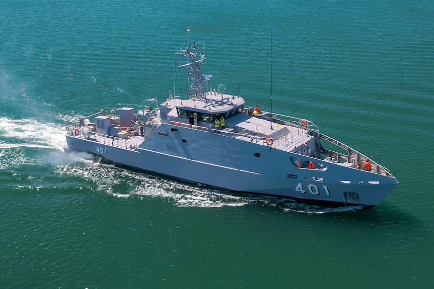 A patrol boat in the middle of the frame moving toward the right on a green-blue ocean