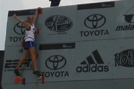 Libby Hall gives a thumbs up from the top of a climbing wall.