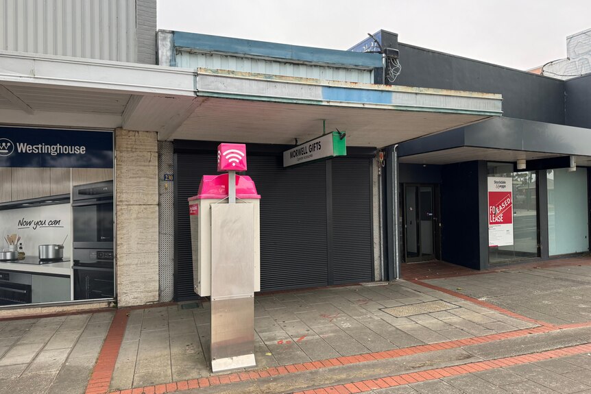 Morwell Gifts shop front is closed up with a Telstra phone box in front of it.