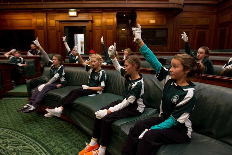 Students wearing white gloves and raising their hands in Old Parliament House.