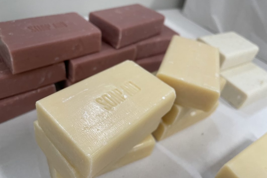 Several piles of brown, white and cream soap bars with the words Soap Aid pressed into them.