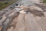 Large holes in the road filled with water from rain.