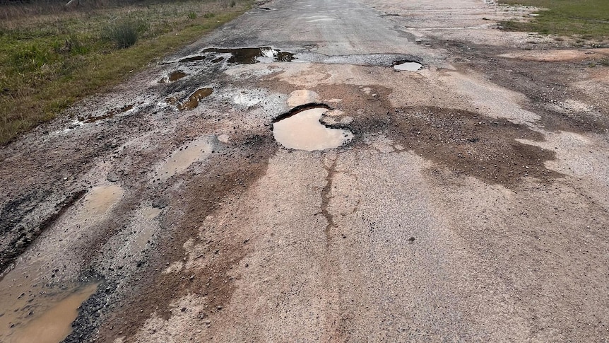 Large holes in the road filled with water from rain.