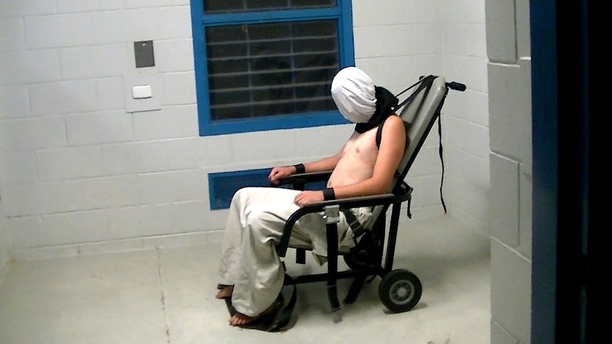 Hooded boy strapped to chair