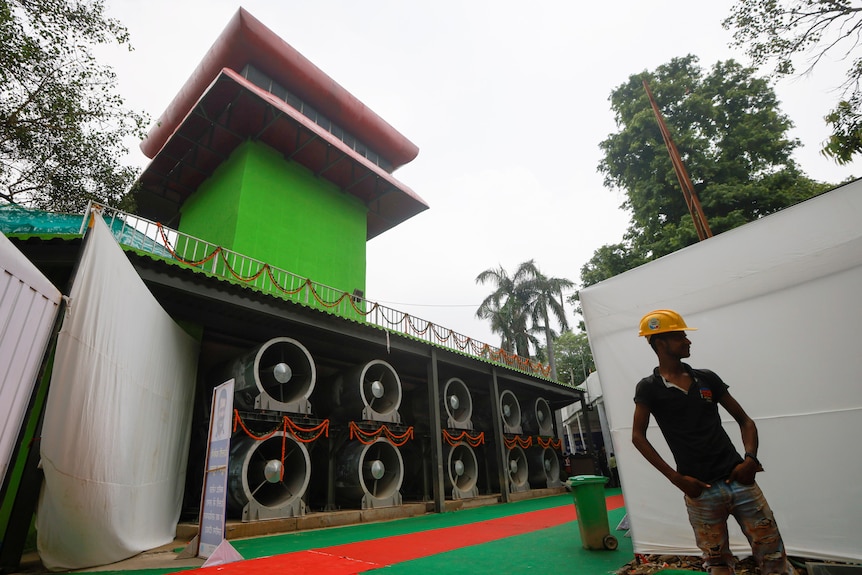 A worker stands next to 20-meter-tall air-purifier.