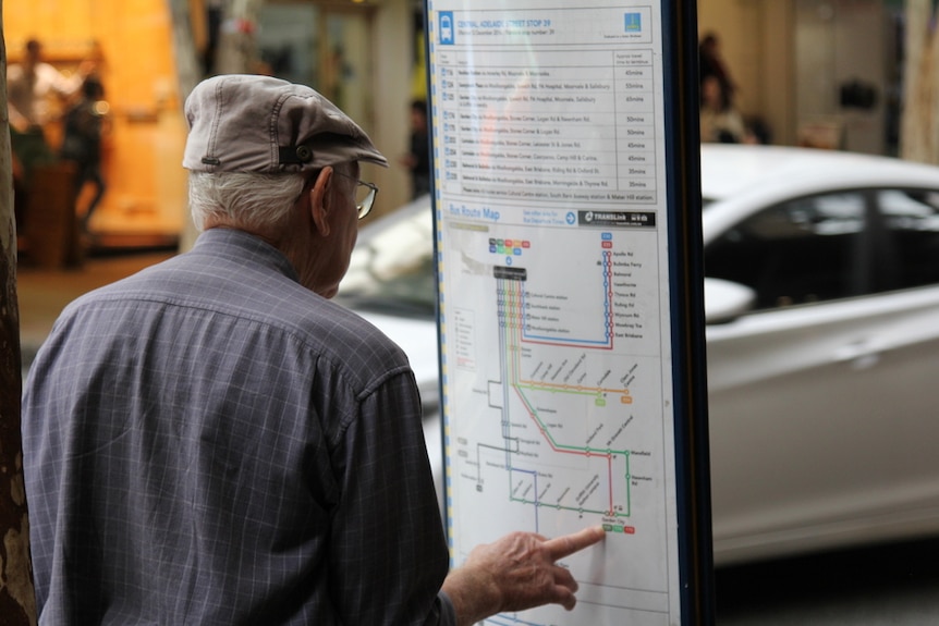 An elderly man looks at a bus timetable sign in Brisbane CBD in June 2018.