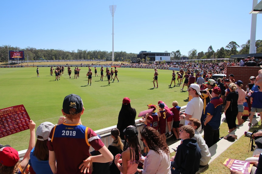 A crowd gathers around the field as the Brisbane Lions begin training