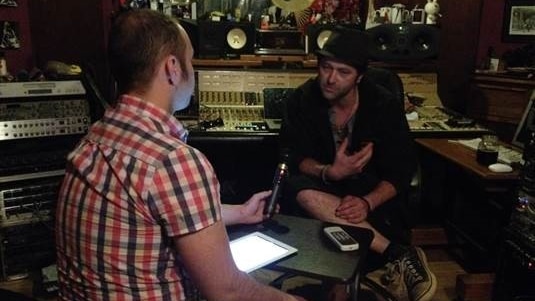 A man interviewing another man in a recording studio