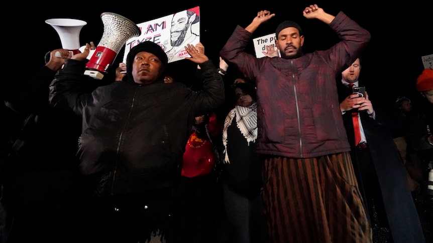 Men hold their hands above their heads and look down in a protest over the death of Tyre Nichols.