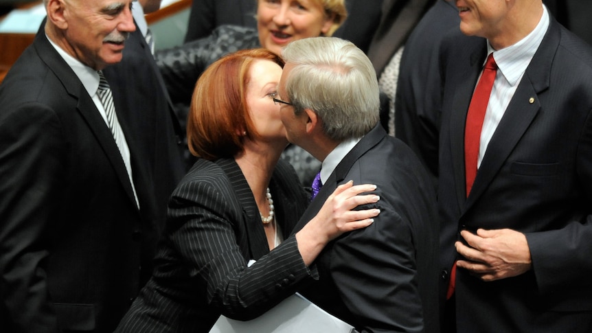 Julia Gillard hugs and kisses Kevin Rudd after the carbon tax legislation was passed in the House of Representatives in Canberra