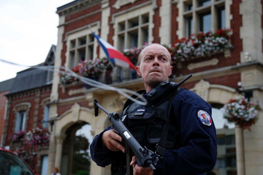 A policeman stands guard in front of the city hall in Saint-Etienne-du-Rouvray.