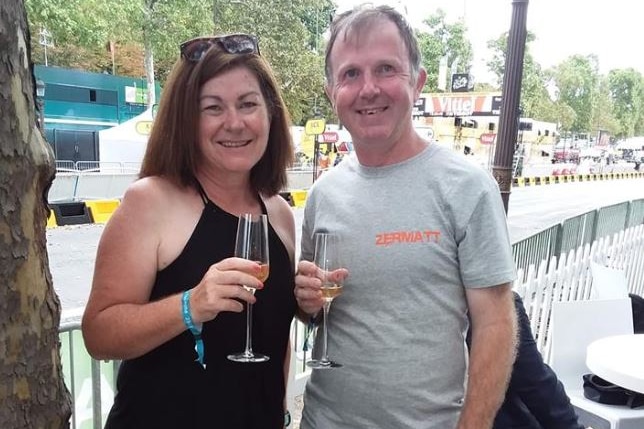 A man and a woman each hold a glass of champagne