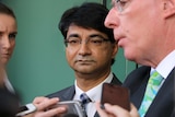 Lloyd Rayney looks stony-faced as his lawyer Martin Bennett speaks to reporters holding mobile phones and microphones.