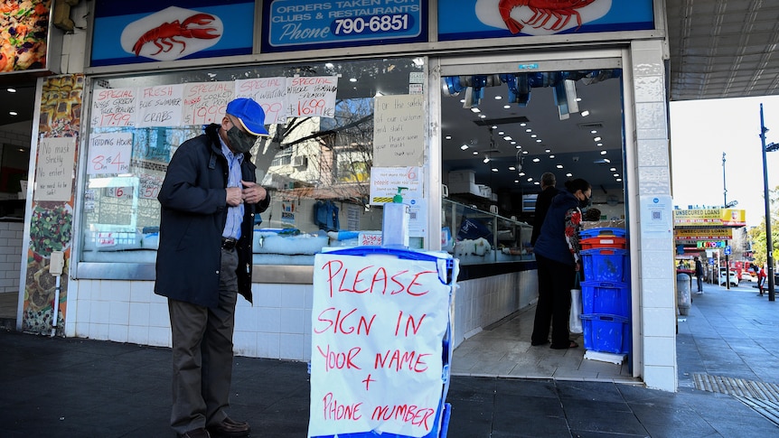 A shopper wearing a face mask signs into a seafood store before entering in Bankstown.