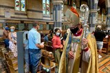 A bishop walks through a church with a facemask