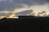 A photo of the Coffs Harbour WWII Bunker take at night, showing the hill and the ocean around it