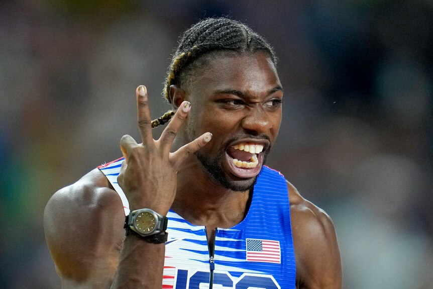 American sprinter Noah Lyles holds up three fingers and yells after a race at the athletics world championships.