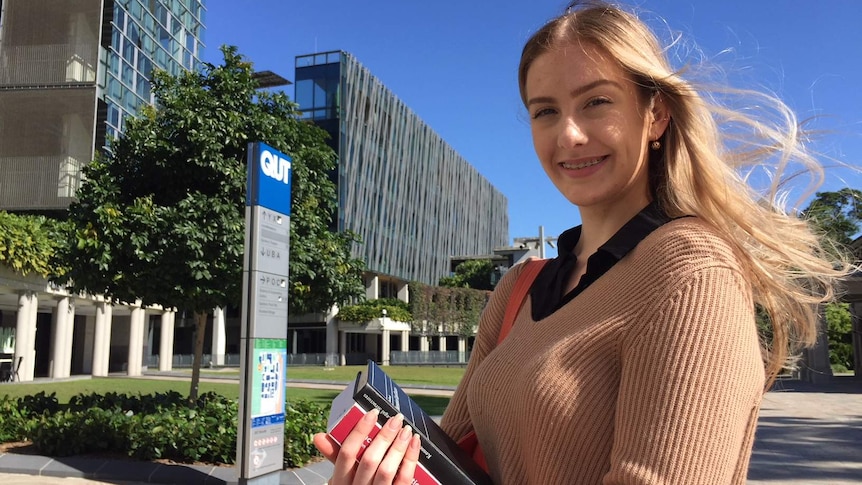 Hannah Taylor holds law textbooks outside a university.