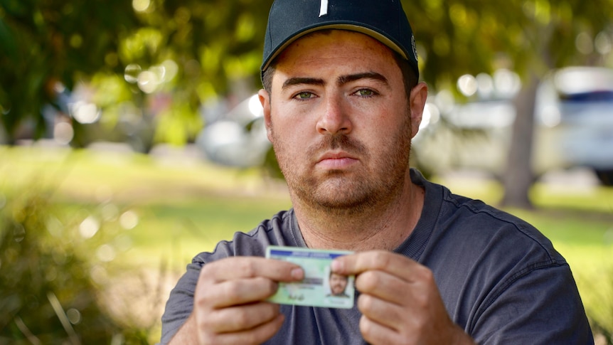 A man holding his licence in a park