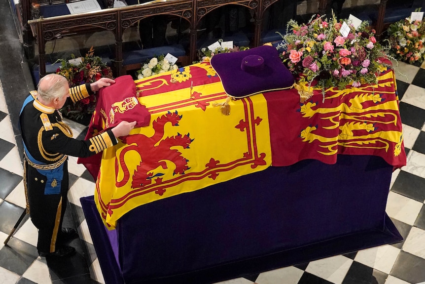 King Charles places the Queen's Company Camp Colour of the Grenadier Guards on the Queen's coffin.