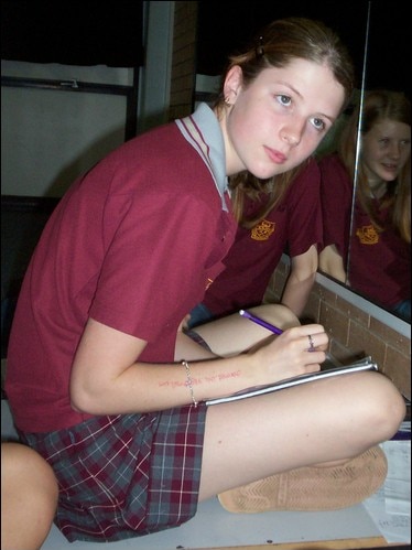 Emma Taylor in a high school uniform, writing in a notebook