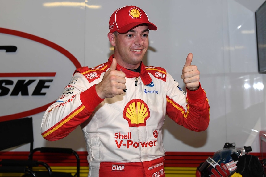 Scott McLaughlin, wearing his racing kit covered in advertising, smiles and gives two thumbs up.