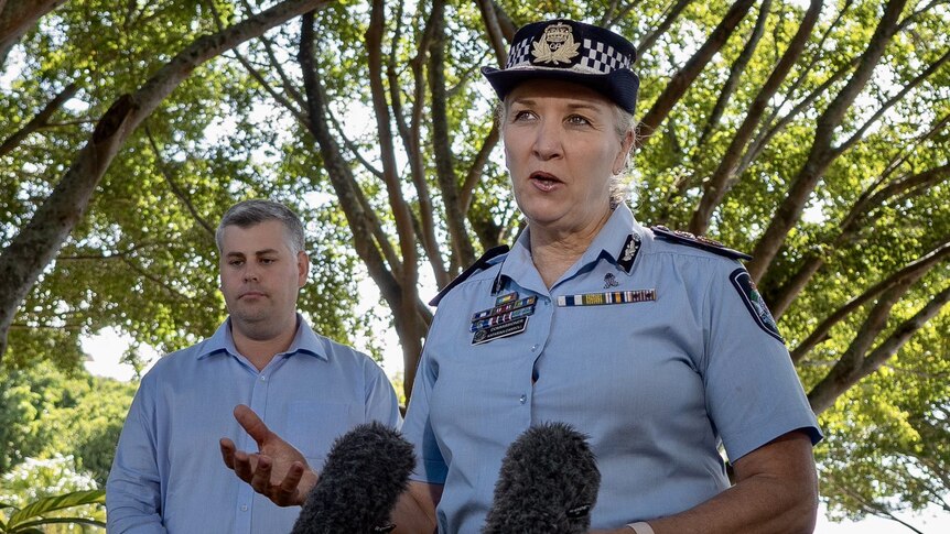 A woman in a police uniform standing in front of a microphone next to a man in a blue shirt