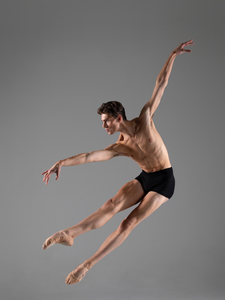 A young man dressed in ballet shorts in full flight mid-air of his dance routine.
