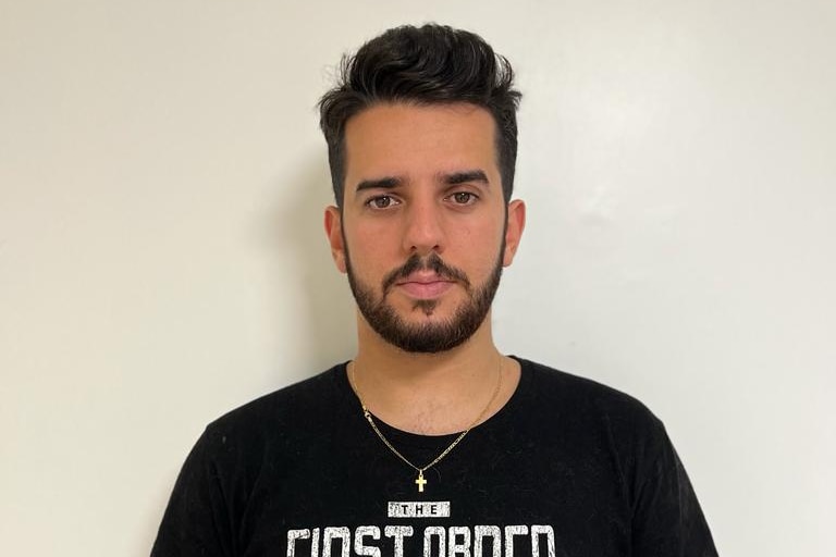 A headshot of a young man wearing a black t-shirt.