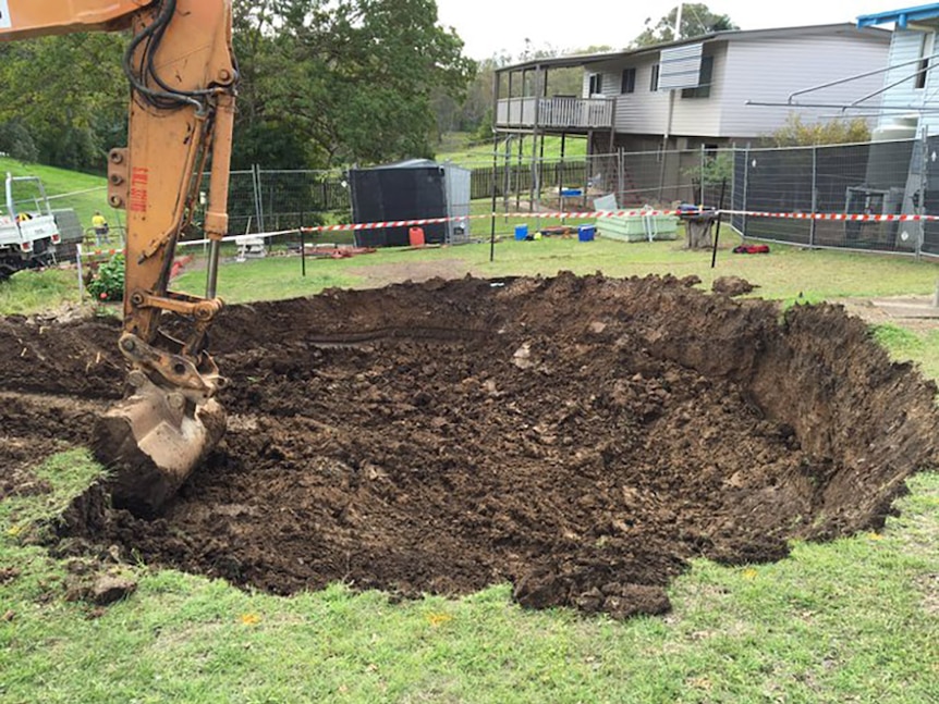 Earthmover works to fill in the sinkhole in the Ipswich backyard