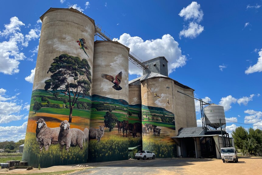 Large grain silos with a painting of a farm and animals on it.