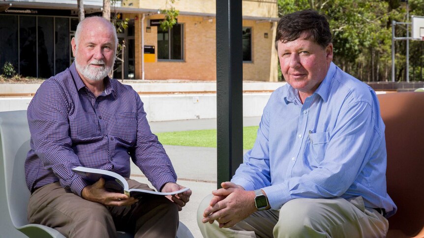 Mike Hazelton and Simon Swinson sit on chairs in a university courtyard.